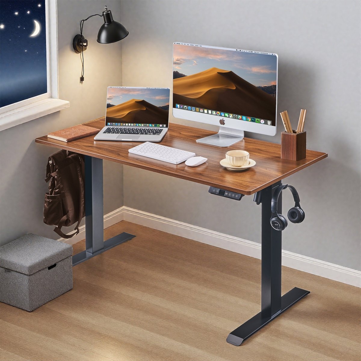 Front view of electric standing desk with computer setup and headphone hook